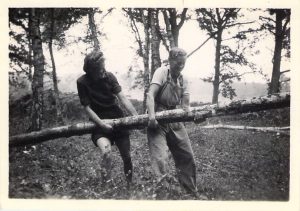 Spenny and another Lumber Jill carrying the trunk of a tree.